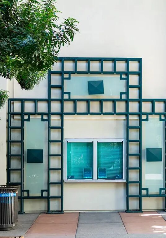Exterior shot of the Frued Playhouse box office, a white building with blue tinted windows and green patterned detailing.
