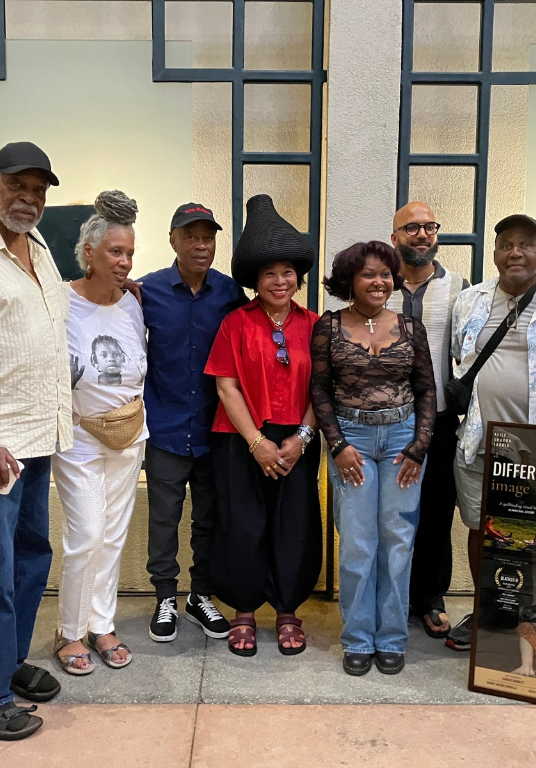 A group of activists and scholars pose for a group photo against a white wall in Macgowan Courtyard.